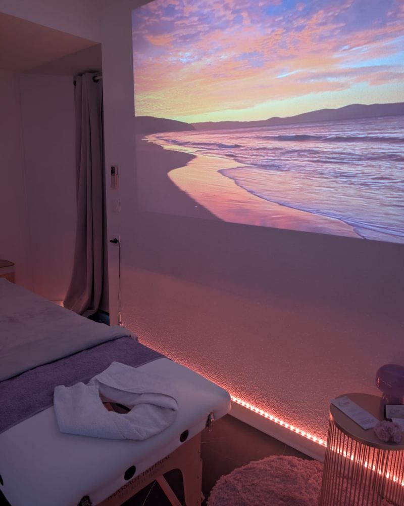 La salle de soin plongée dans une ambiance de coucher de soleil sur la plage, projetée sur le mur