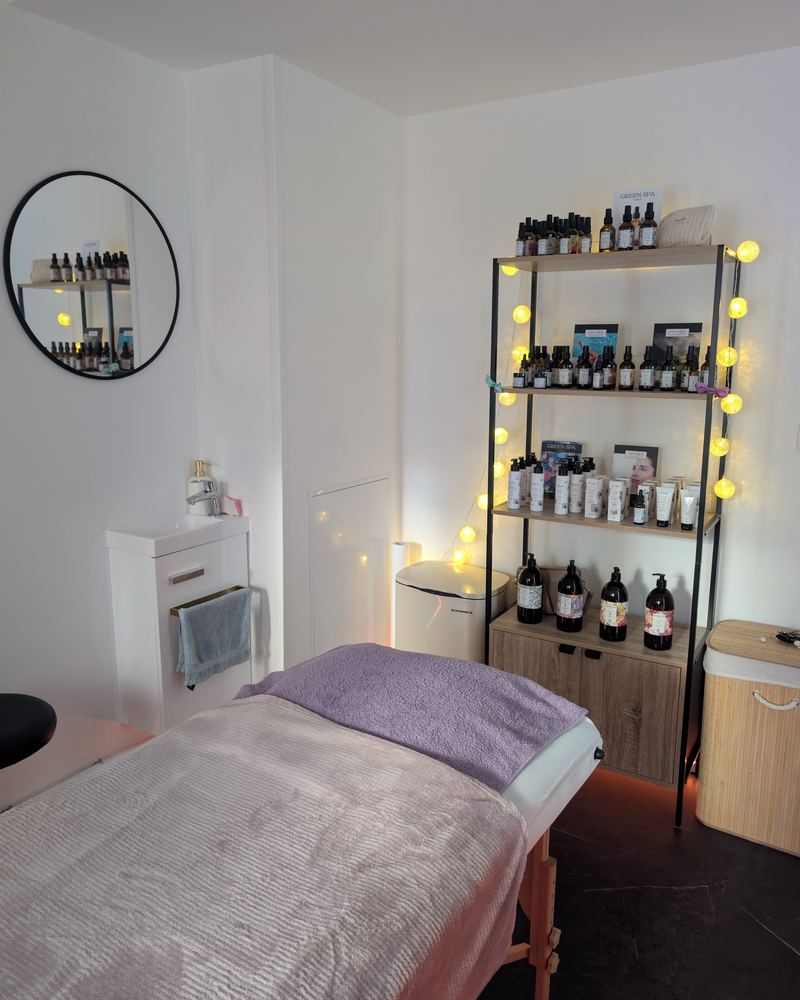 L'étagère de produits Green Spa, éclairée de guirlandes lumineuses, à côté de la table de soin