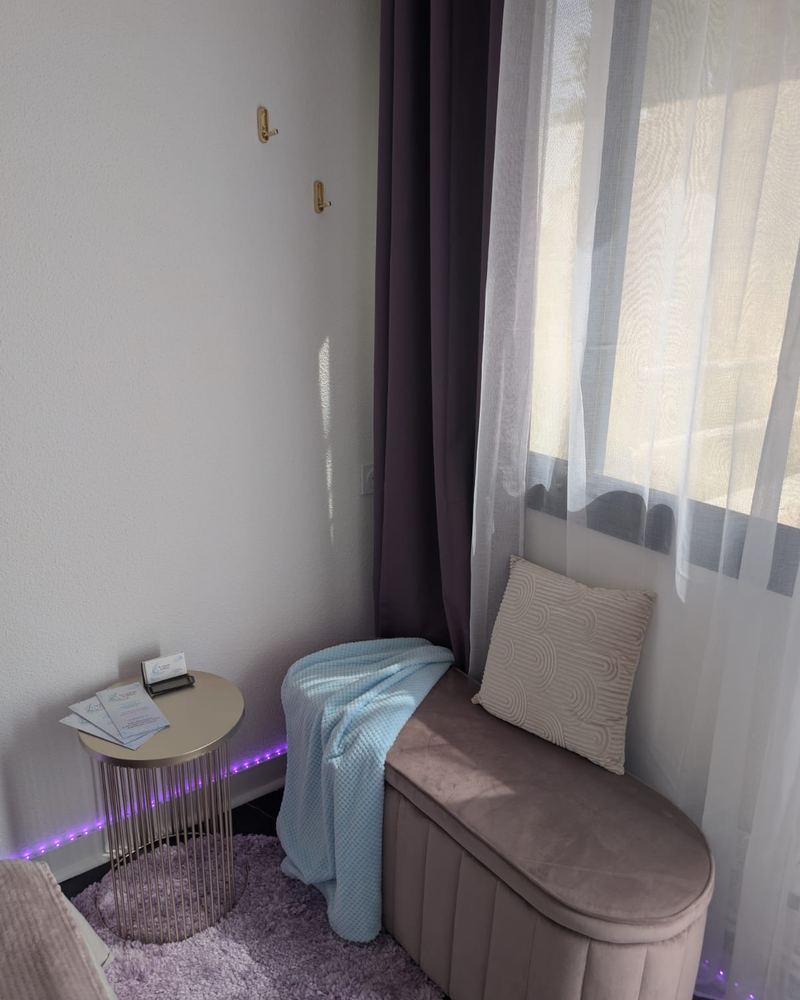 Le coin détente : banquette rose, plaid bleu, guéridon doré et rideaux prune