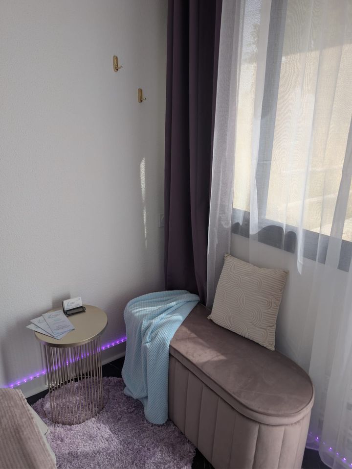 Le coin détente : banquette rose, plaid bleu, guéridon doré et rideaux prune