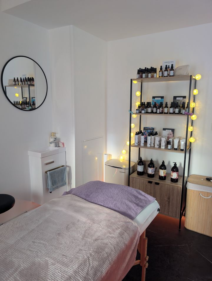 L'étagère de produits Green Spa, éclairée de guirlandes lumineuses, à côté de la table de soin