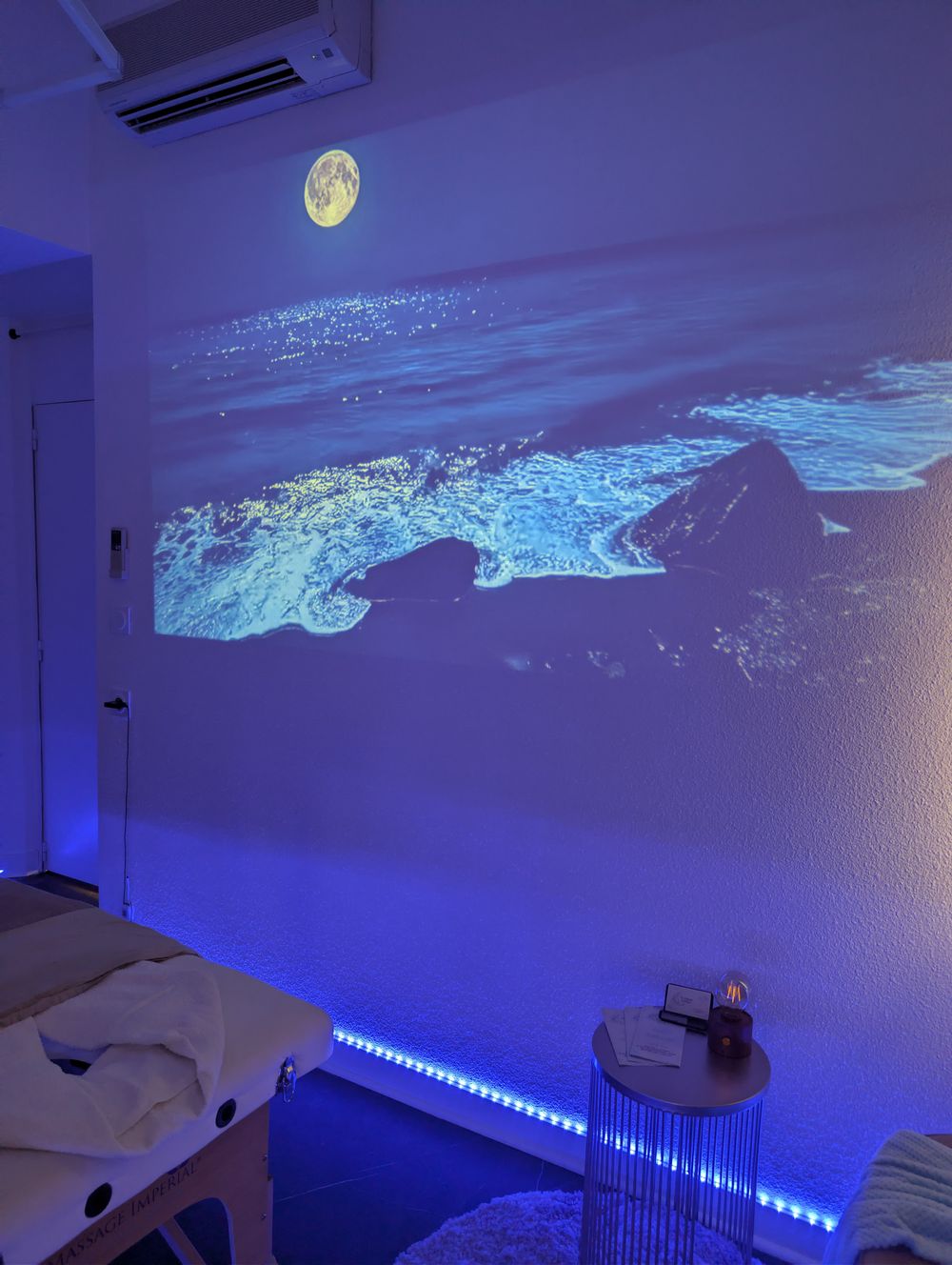 Au clair de lune : la salle de massage, avec une plage sous la pleine lune projetée sur le mur